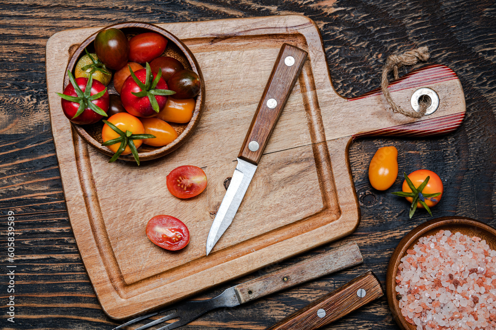 Wall mural ripe cherry tomatoes and knife on cutting board. Dark wooden table. View from above.