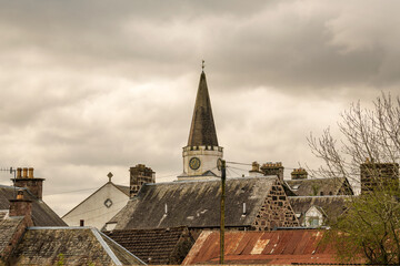 moody shot of roof lines and a church spire in a victorian era scottsih village somber heavy clouds