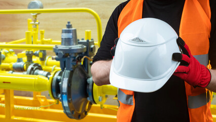 Man with protective helmet. Industrialist near pipes. White helmet with piping. Guy is holding hardhat. Industrial background. Worker in oil and gas industry. Factory safety helmet.