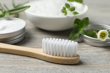 Fototapeta na wymiar Toothbrush, sea salt and green herbs on wooden table, closeup