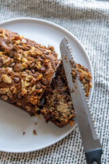 Fresh cut up homemade banana bread with chocolate chips and walnuts on a white ceramic plate