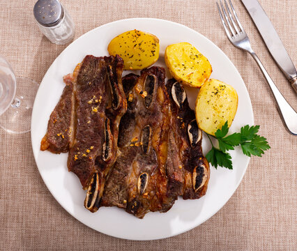 Spanish cuisine churrasco de ternera, spare ribs with potatoes on a ceramic plate