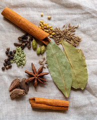 Whole colourful spices for making Indian Garam Masala displayed on a natural linen cloth