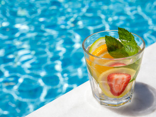 Citrus and strawberry infused water, cocktail, lemonade in glass near pool