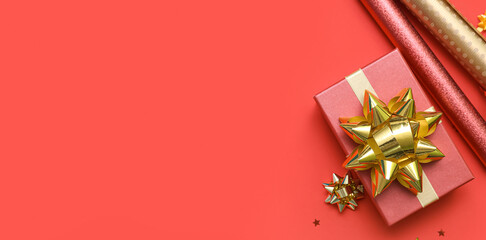 Gift box and wrapping paper on red background with space for text