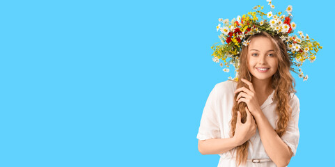 Beautiful young woman in flower wreath on blue background with space for text. Summer solstice - obrazy, fototapety, plakaty