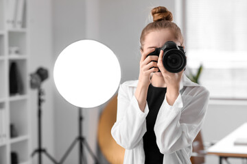 Young female photographer with professional camera in studio