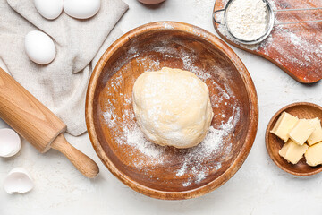 Bowl with raw dough for Italian Easter bread and ingredients on white background