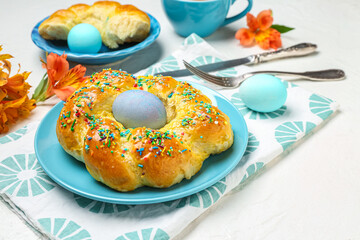 Plate with tasty Italian Easter bread and eggs on light background