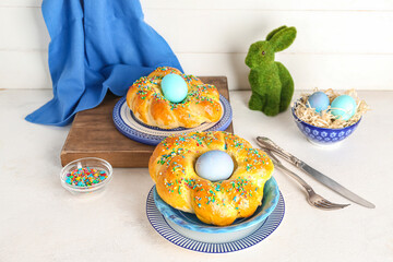 Plates with tasty Italian Easter bread, eggs and colorful sprinkles on light table