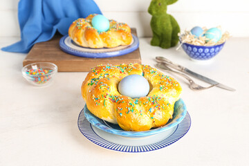 Plates with tasty Italian Easter bread, eggs and colorful sprinkles on light table
