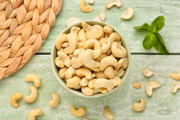 Bowl with tasty cashew nuts on light wooden background