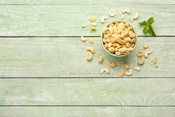 Obraz na płótnie Canvas Bowl with tasty cashew nuts on light wooden background