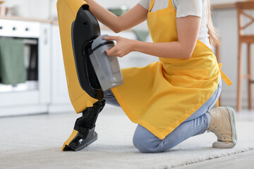 Young woman with vacuum cleaner in kitchen, closeup