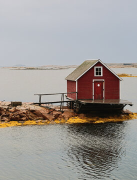 Red Boathouse on Rocky Coast with Calm Water