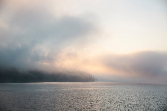 Misty Coastal Landscape at Sunrise with Calm Water