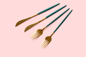 Stylish forks and knives on pink background