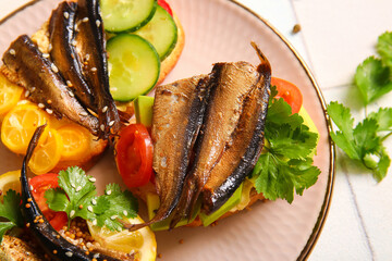 Plate of tasty sandwiches with canned smoked sprats on table