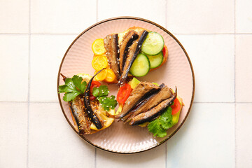 Plate of tasty sandwiches with canned smoked sprats on white tile background
