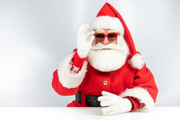 Portrait of santa claus sitting with his arms folded at a white table. 