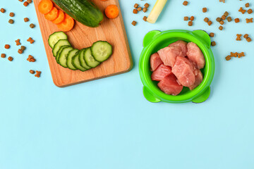 Dry pet food, raw meat and natural products on blue background