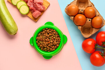 Bowl with dry pet food, raw meat and natural products on color background