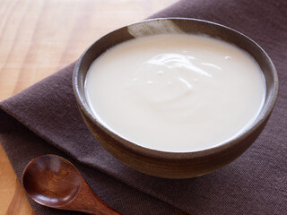 Close up, Homemade greek yogurt or sour cream in old clay bowl with wooden spoon on brown napkin background. Food helps the digestive system. space for your text. .