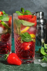 Glasses of delicious strawberry mojito on dark background, closeup