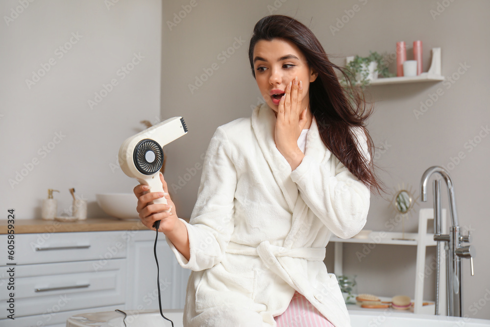 Canvas Prints Surprised young woman with hair dryer in bathroom