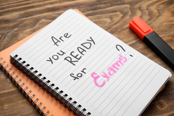 Notebooks with question ARE YOU READY FOR EXAM? and marker on brown wooden background