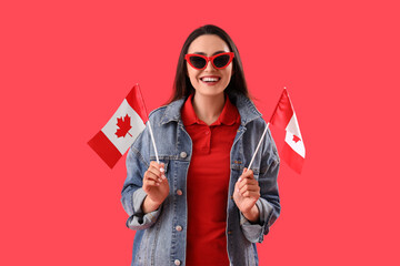 Young woman with flags of Canada on red background