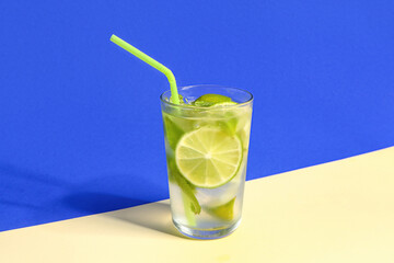 Glass of cold mojito on colorful background