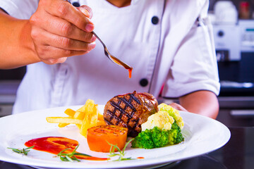The chef at the restaurant carefully drenches the sauce onto the fresh meat on the plate to create an appetizing