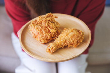 Closeup image of a woman holding a plate of fried chicken