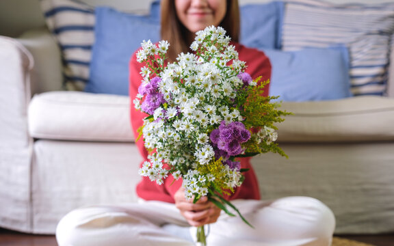 Closeup image of a young woman holding flower bouquet at home