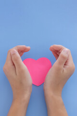 Closeup,Child's hands with a red heart on blue background.Give love philanthropy,help warmth and take care,protect children's health,blood donation and stem cell,valentines day concept.Space for text.