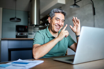 Middle aged man working on his laptop and going over his bills at home