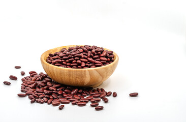 The close-up of raw organic red beans in a round shape wooden bowl on white background with a small...