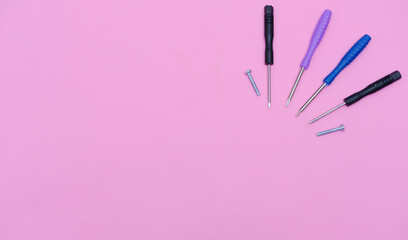 Small screwdrivers for phone repair on a pink background. Layout with space to copy pink color. A blank for advertising smartphone or gadget repair services