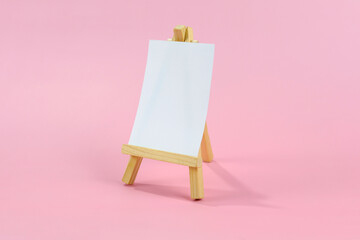 Easel with paper for writing messages or pictures. on a pink background