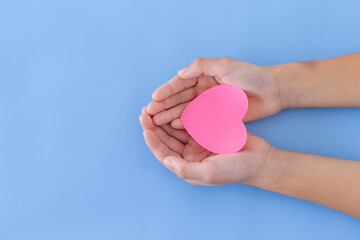 Closeup,Child's hands with a red heart on blue background.Give love philanthropy,help warmth and take care,protect children's health,blood donation and stem cell,valentines day concept.Space for text.