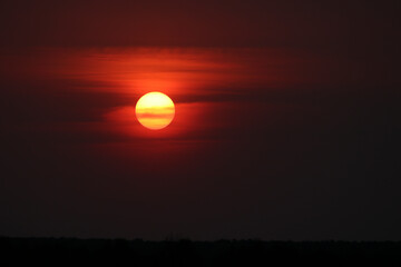Romantic sunset, dramatic background, red sun with spots.