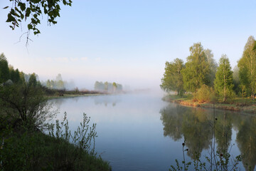 Fototapeta na wymiar Summer morning on the river with fog, birches on the shore. Travel outdoors.