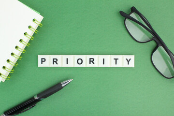 glasses, pen and notebook with the word priority. priority concept. priorities in life 