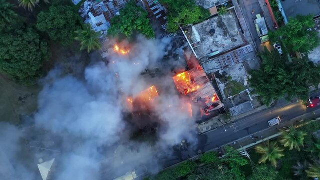 Aerial view above firefighters extinguishing a building fire - screwdriver, drone shot