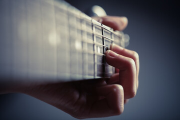 color detail of hands playing of an old acoustic guitar