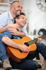 loving gay couple resting with guitar at home