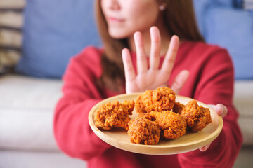 Closeup of a woman making hand sign to refuse fried chicken for dieting and healthy eating concept