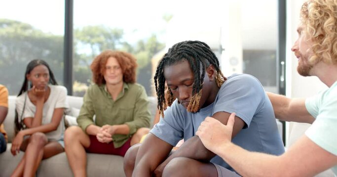 Emotional diverse male friends talking and embracing during group therapy session, slow motion