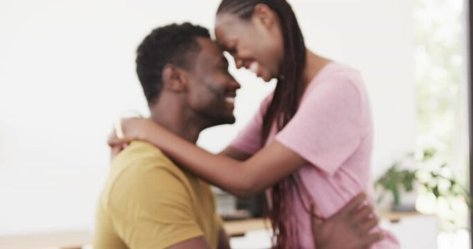 Happy african american couple smiling and embracing in living room, in slow motion